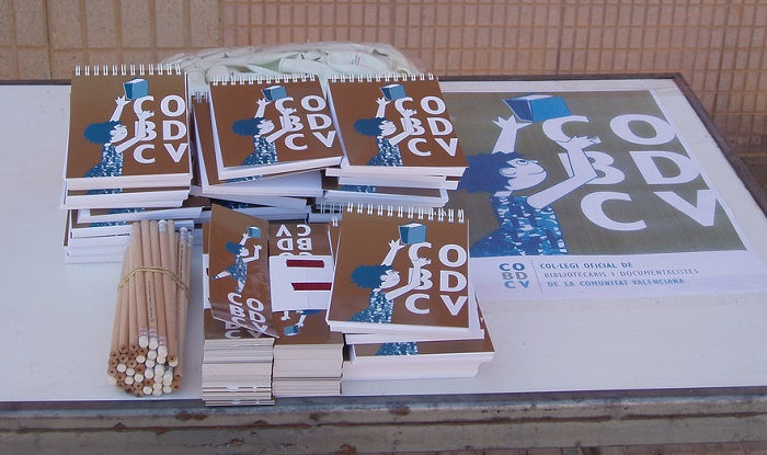 Foto de materiales promocionales del COBDCV (libretas, lápices, marcapáginas, cartel)